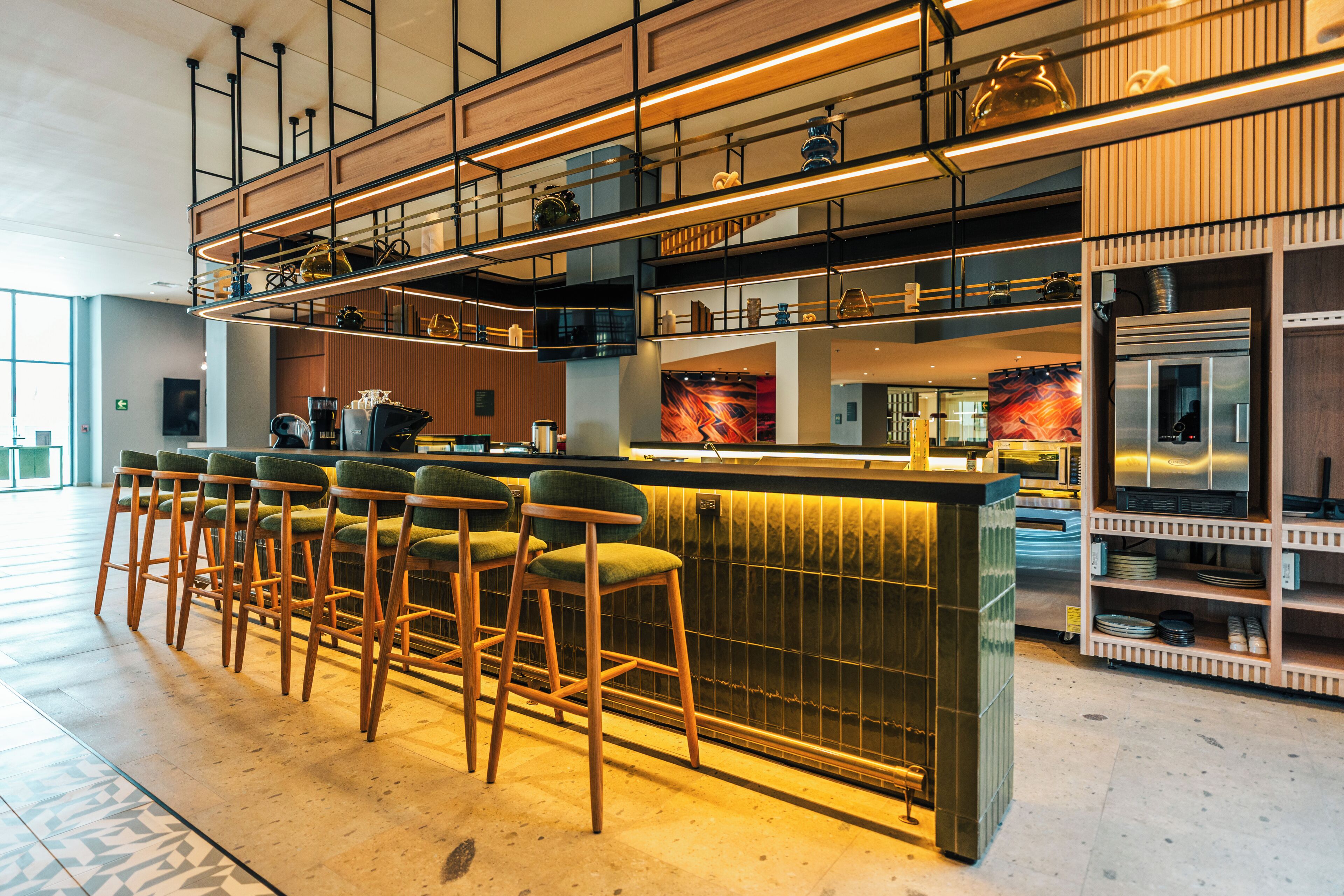 A modern bar area with high stools, a counter, and a kitchen in the background.