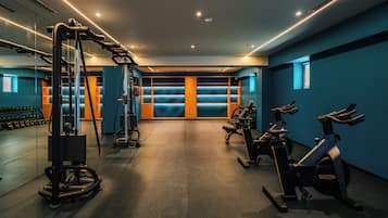A gym with exercise equipment, a mirrored wall, and a blue wall with a window.