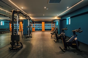 Un gimnasio con equipo de ejercicio, un espejo y una pared azul con una ventana.