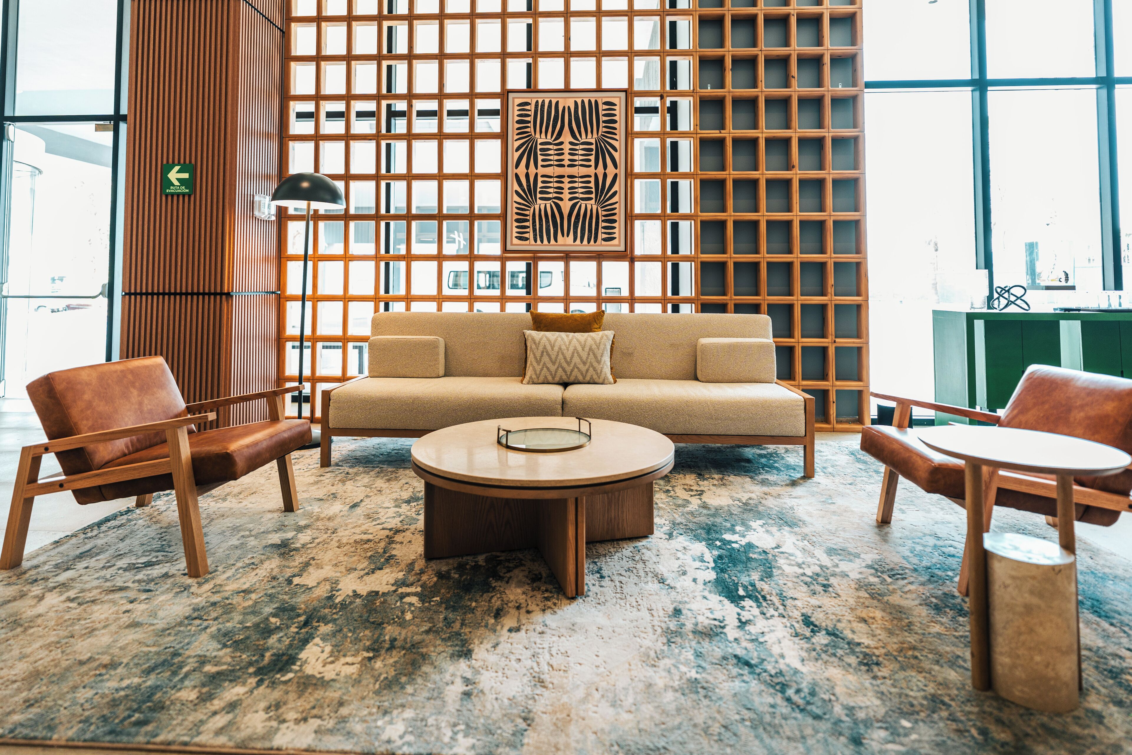 A modern interior with a sofa, two armchairs, a coffee table, and a patterned rug.