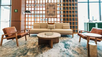 A modern interior with a sofa, two armchairs, a coffee table, and a patterned rug.
