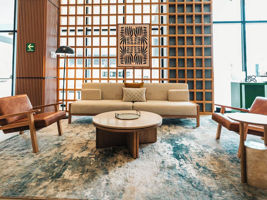 Un interior moderno con un sofá, dos sillones, una mesa de centro y una alfombra estampada.