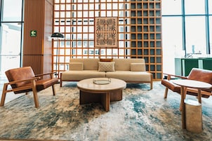 Un interior moderno con un sofá, dos sillones, una mesa de centro y una alfombra estampada.