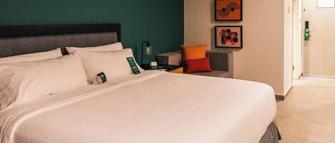 Una camera d'hotel con un letto grande, un comodino e un'opera d'arte appesa al muro.