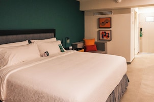 Habitación de hotel con una cama grande, una mesita de noche y una obra de arte colgada en la pared.