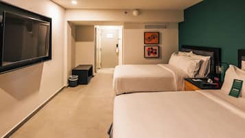 A hotel room with two beds, a TV, a small table, and artwork on the wall.