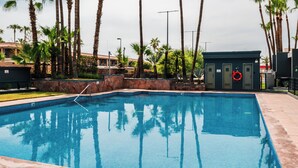 A swimming pool with clear blue water, surrounded by palm trees and a stone wall. - Holiday Inn Mexicali Centro Civico by IHG (Mexicali)