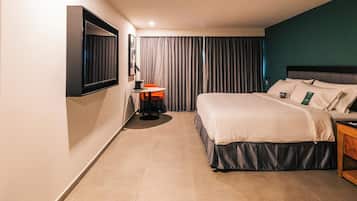 A hotel room with a bed, a desk, a chair, a TV, and curtains.