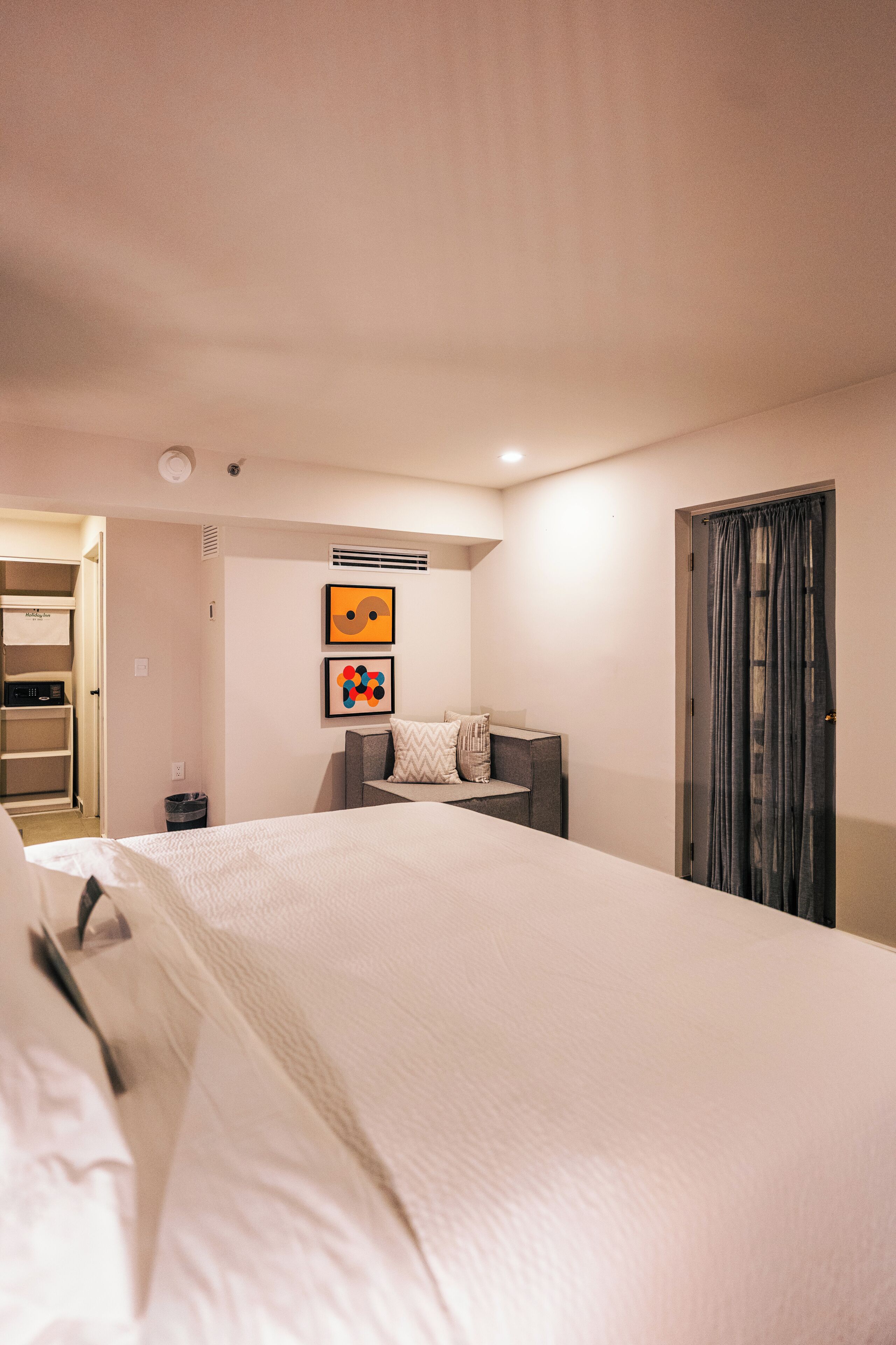 A hotel room with a large bed, a desk, a chair, and a wardrobe.