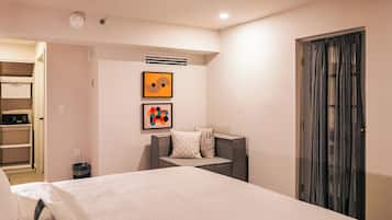 A hotel room with a large bed, a desk, a chair, and a wardrobe.