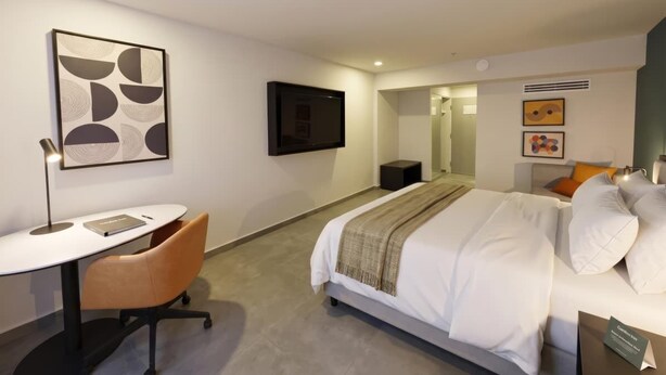 A hotel room with a bed, a desk, a chair, a TV, and artwork on the walls. - Holiday Inn Mexicali Centro Civico by IHG (Mexicali)