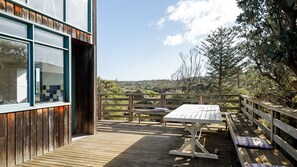 A wooden deck with a table and benches, overlooking a natural landscape.