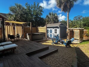 A backyard with a wooden deck, outdoor seating, a hot tub, and a small shed. - (Tarpon Springs)