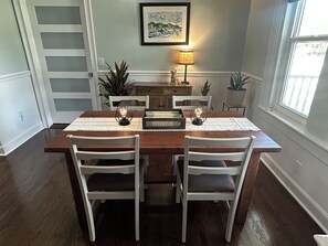 A dining area with a wooden table, white chairs, a decorative centerpiece, and a painting on the wall. - (Tarpon Springs)
