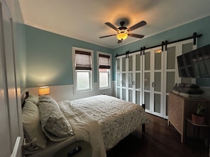 A bedroom with a bed, a ceiling fan, a wardrobe, a television, and a window with blinds. - (Tarpon Springs)
