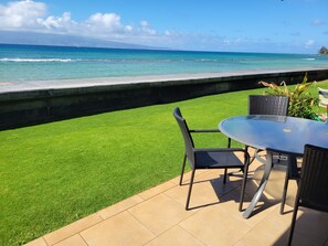 A patio with a table and chairs overlooking a beach with waves. - Exquisite Direct Sunset & Oceanview 4 Miles! Pool (Lahaina)
