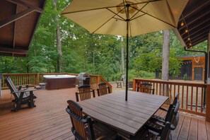 A wooden deck with a table and chairs, a hot tub, and a grill. - The Lodge at Rivers Edge Retreat | Hot tub + Pickleball (Malvern)