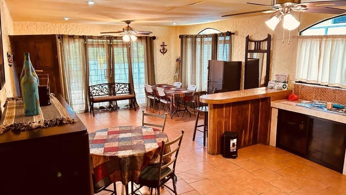 Zona pranzo con tavolo rotondo, sedie e bancone bar.