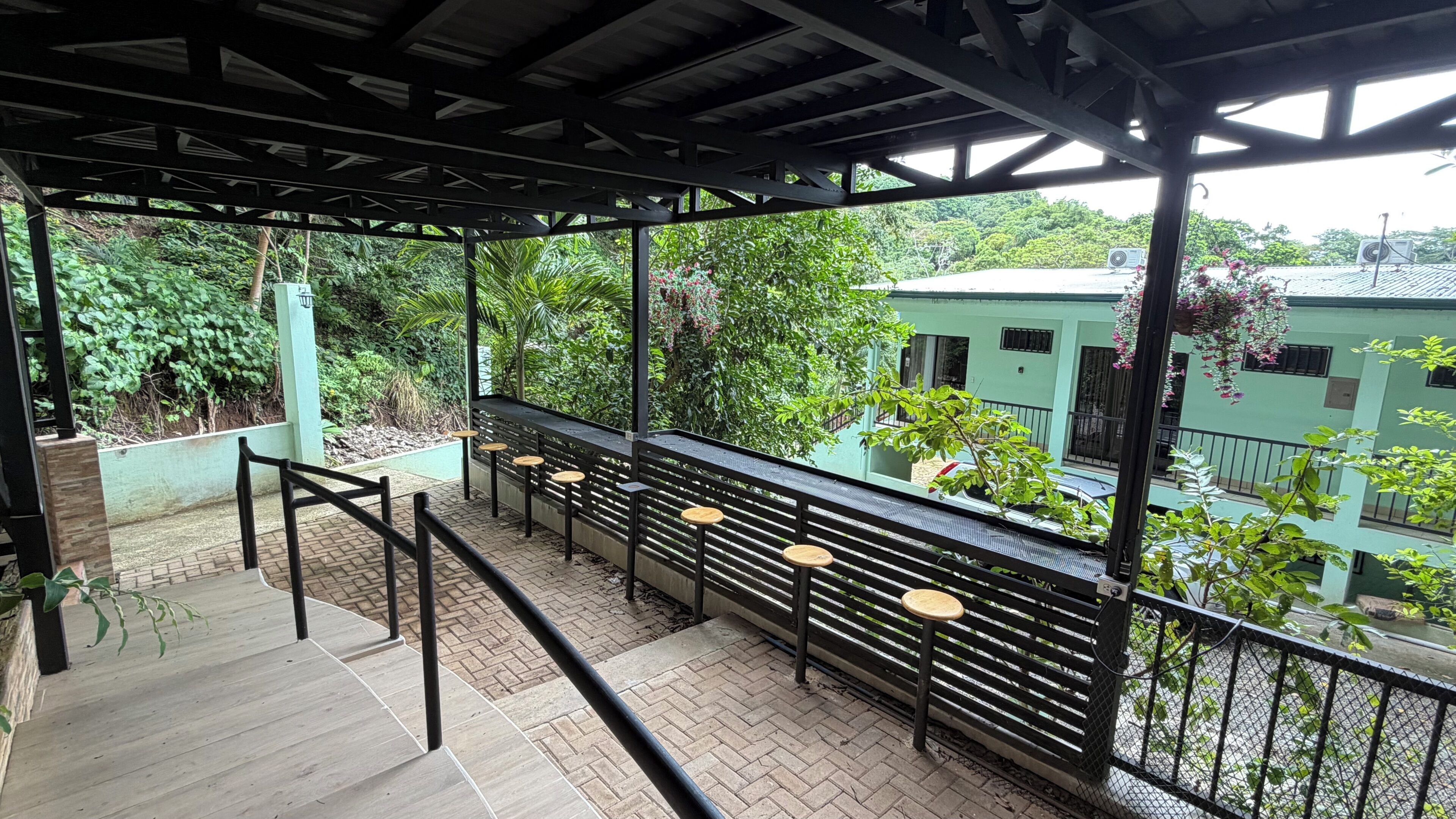 A covered outdoor seating area with a view of a residential building and greenery.