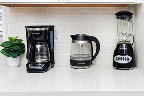 A kitchen counter with a coffee maker, a kettle, and a blender. - Stylish 2bed room Apt Near Hospitals Golf course and Beaches (St. Petersburg)