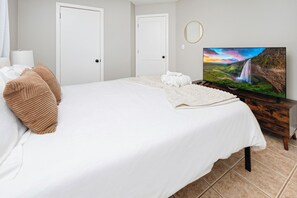 Een hotelkamer met een groot bed, een televisie op een houten standaard en een afbeelding van een waterval op de muur.