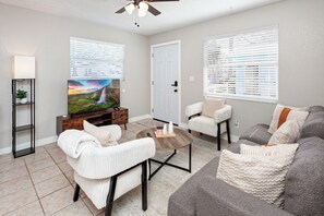 A living room with a television, seating, and a door. - Stylish 2bed room Apt Near Hospitals Golf course and Beaches (St. Petersburg)