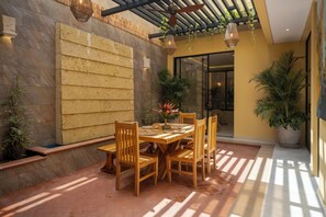 Eine Terrasse mit einem Holztisch und Stühlen, umgeben von Steinmauern und Topfpflanzen.