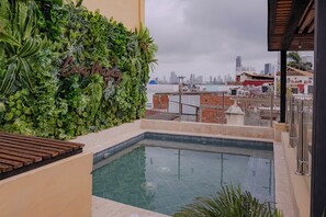 A rooftop pool with a city view, surrounded by lush greenery and a wooden deck. - Casa Maguey | Rooftop Jacuzzi, Bay Views & Culture (Cartagena de Indias)