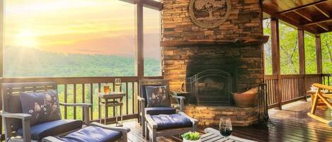 A wooden deck with outdoor seating, a fireplace, and a scenic view.