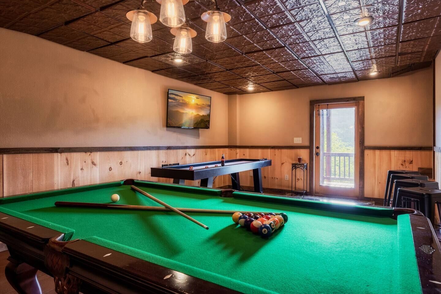 A pool table with balls and cues, a billiard table, and a painting on the wall.