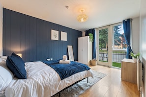 Ein Schlafzimmer mit Bett, Kleiderschrank, Schreibtisch und Blick ins Freie.