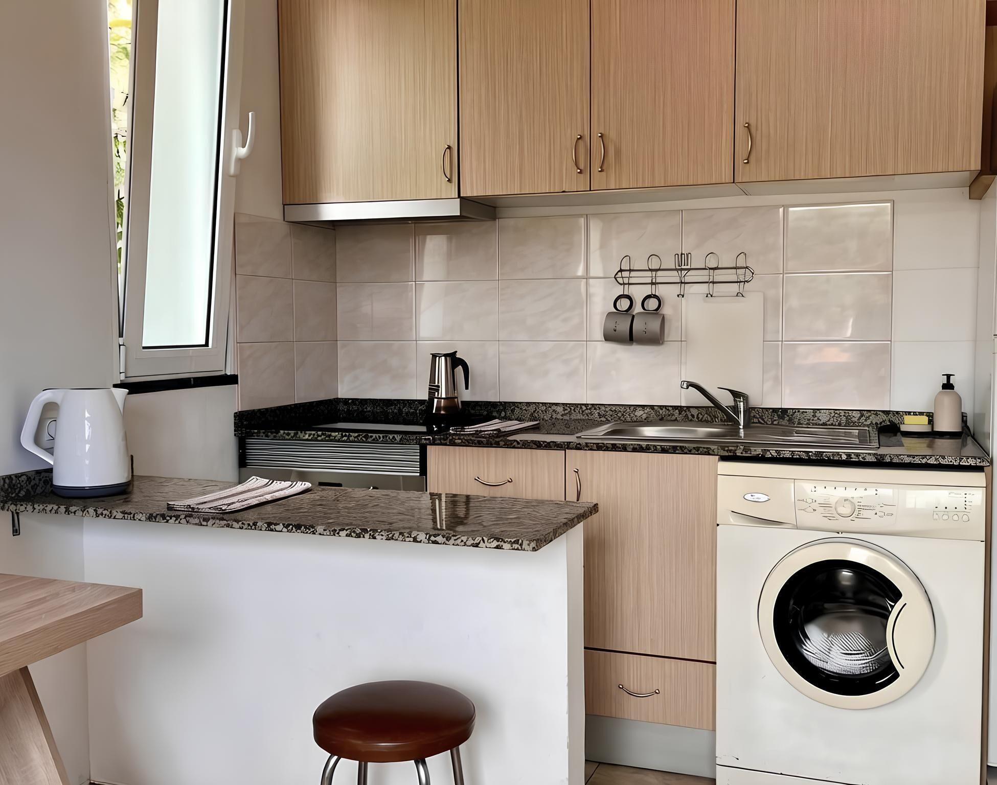 A compact kitchen with a washing machine, a coffee maker, and a sink.