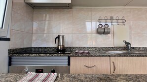 A kitchen with wooden cabinets, a stainless steel kettle, a granite countertop, a sink, and a wall-mounted utensil holder. - Recharge in this peaceful and stylish place. (Funchal)
