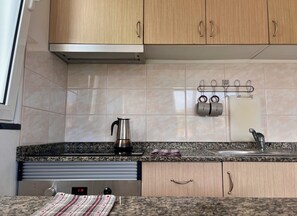 A kitchen with wooden cabinets, a stainless steel kettle, a granite countertop, a sink, and a wall-mounted utensil holder. - Recharge in this peaceful and stylish place. (Funchal)