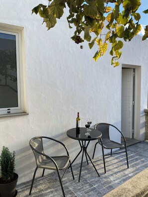 An outdoor patio with two chairs, a table, a bottle of wine, and a glass of wine. - Recharge in this peaceful and stylish place. (Funchal)