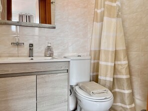 A bathroom with a toilet, sink, mirror, and shower curtain. - Recharge in this peaceful and stylish place. (Funchal)