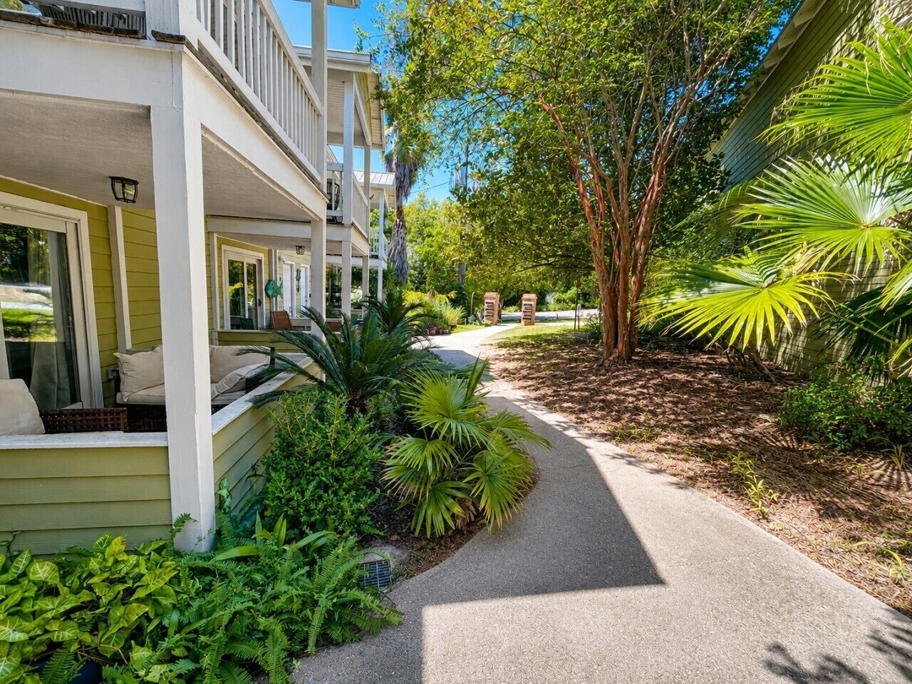 A residential property with a covered porch, a pathway, and lush greenery.