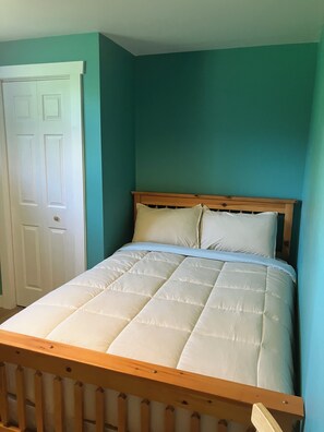 Ein Einzelbett mit Holz Kopfteil und weißer Bettwäsche in einem Zimmer mit türkisfarbenen Wänden.