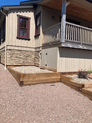 A wooden building with a stone foundation, a wooden deck, and a gravel driveway. - Georgetown Ranch Rental - Great For Families & Golfers! (Georgetown)