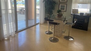 Uma cozinha moderna com uma ilha de vidro, banquetas e um vaso de planta.
