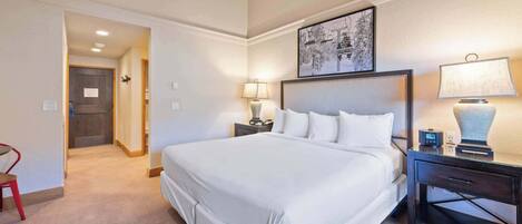 Habitación de hotel con una cama grande, dos mesitas de noche con lámparas, un ventilador de techo y un cuadro en la pared.