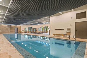 Ein hallenbad mit klarem Wasser, Holzliegen und einem modernen Deckenbau.