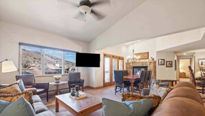 Amplia sala de estar con un gran ventanal, televisor de pantalla plana, chimenea y comedor.