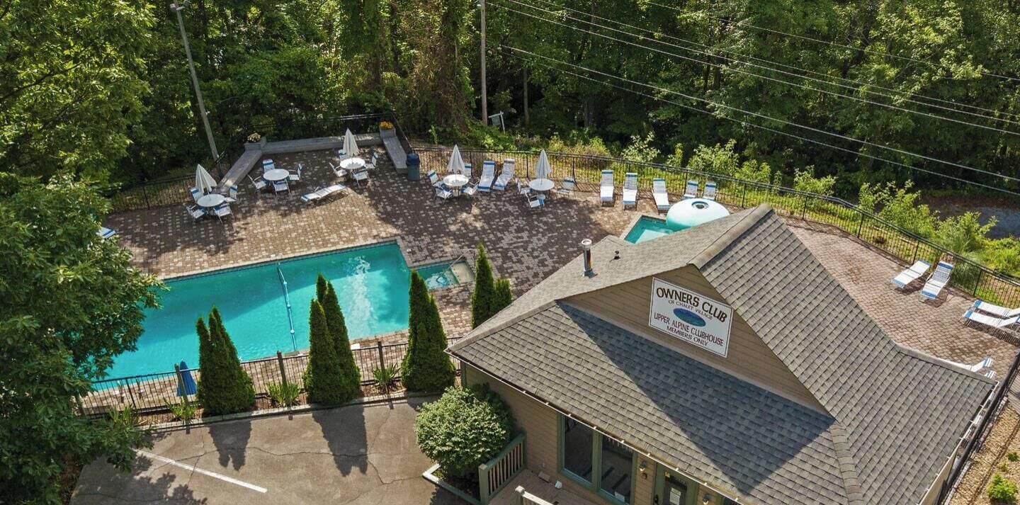 Un área de piscina con sillas de descanso y un cartel para el Club de Propietarios.