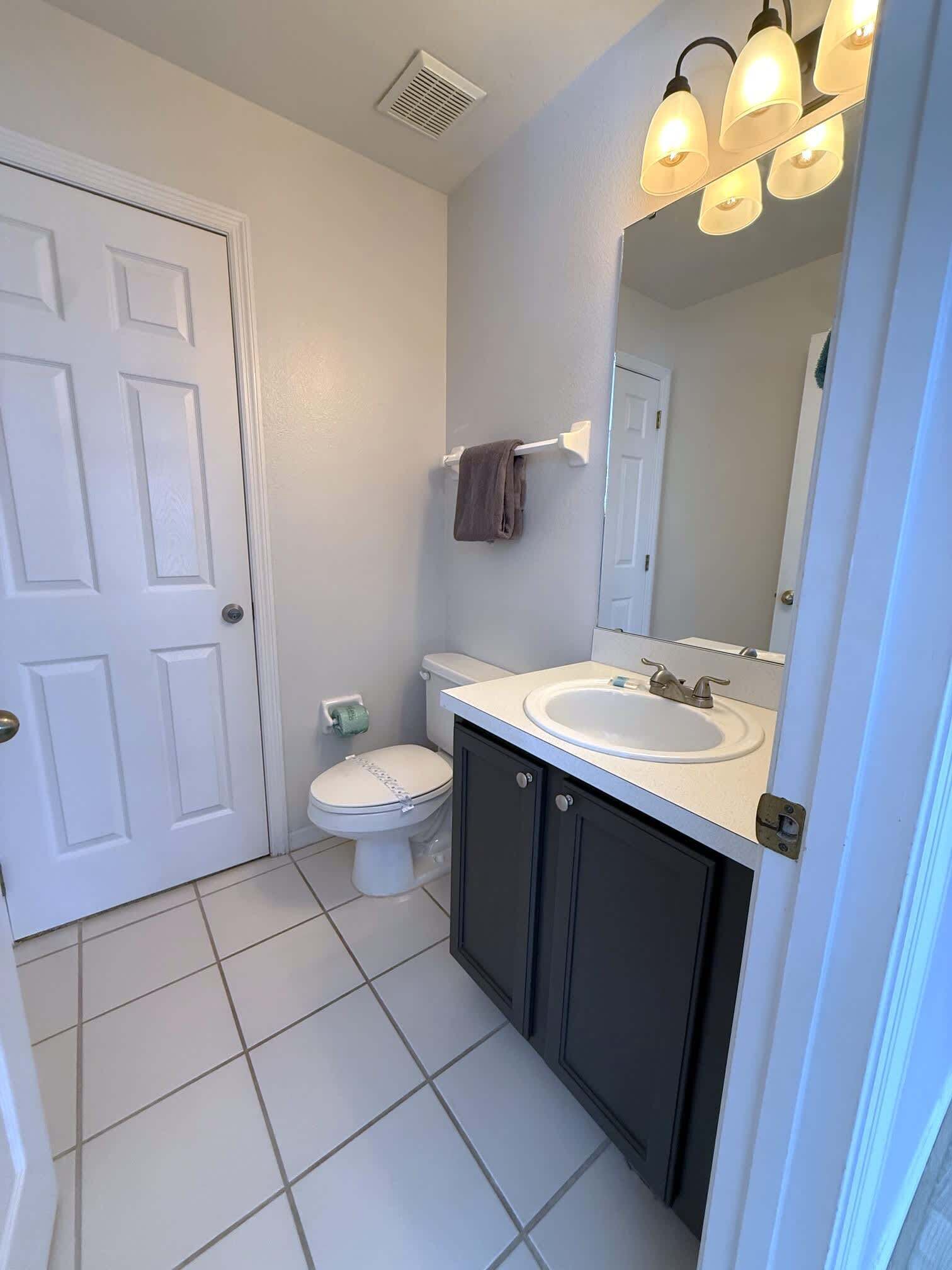A bathroom with a toilet, sink, and mirror.
