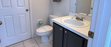 A bathroom with a toilet, sink, and mirror.