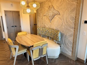 A dining area with a round wooden table, cushioned chairs, and a bench. - Orlando | Couples Island Escape | Pool + Beach (Golden Oak)