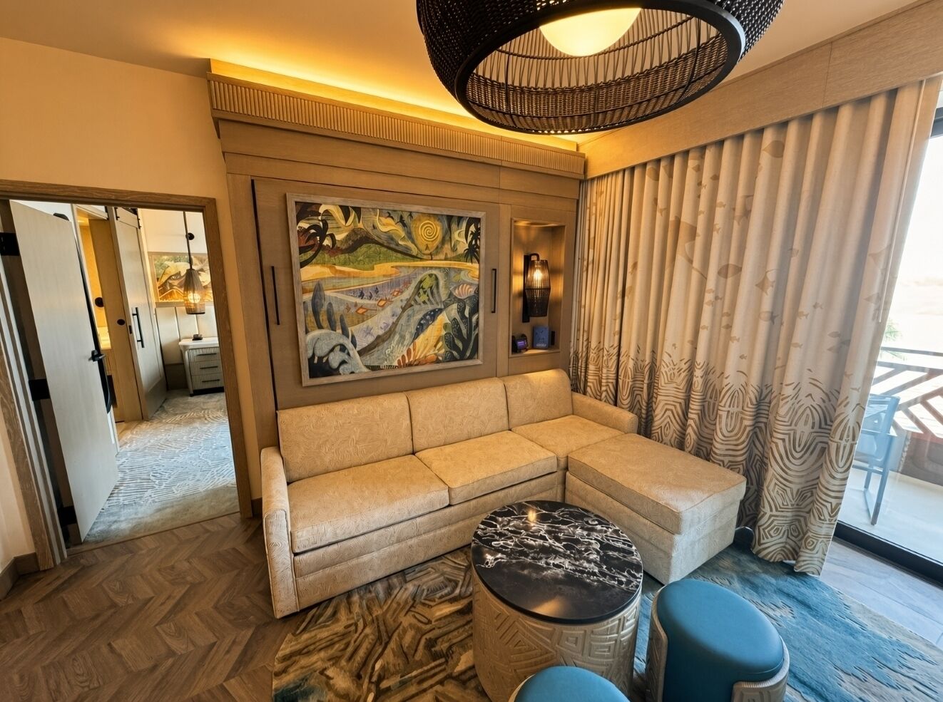 A modern living room with a beige sofa, a round coffee table, and a large abstract painting on the wall.