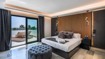 Een moderne slaapkamer met een groot bed, een zithoek met uitzicht en een schuifdeur naar buiten.