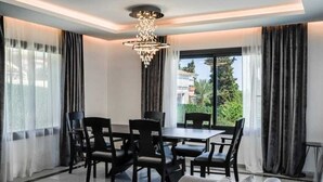 A modern dining area with a chandelier, a dining table with chairs, and a sofa.